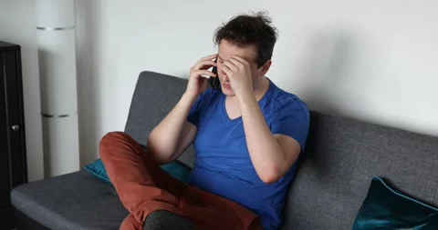 Man sitting on the sofa and talking on the smartphone Stock Footage 131161867
