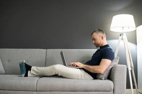 Man Sitting In Sofa And Using Laptop Stock Photos