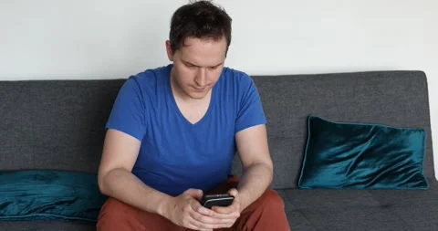 Man sitting on the sofa and watching on the smartphone Stock Footage 131161850