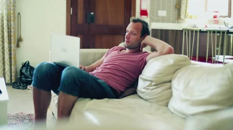 Man sitting on sofa and working on laptop computer Stock Footage 17981526