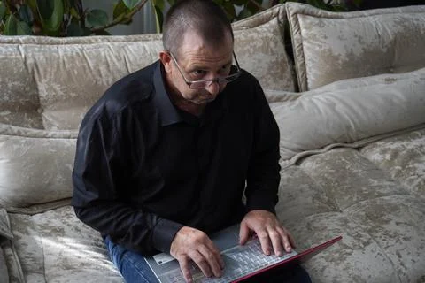 Man sitting on sofa and working on laptop Stock Photos