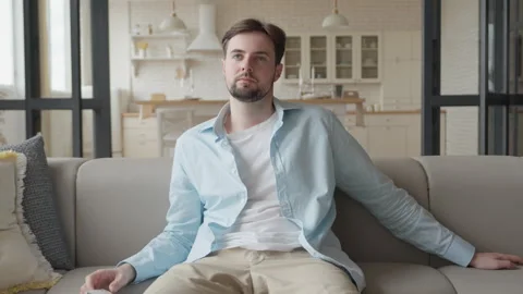 Man Sitting at Sofa in Comfortable Apartment and Watching TV Stock Footage 295194983