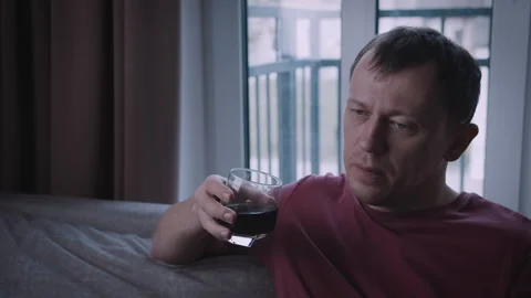 Man Sitting on Sofa with Drink in Hand, Calm Mood by Window Video stock 334320429