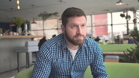 Man sitting on sofa, drinking coffee, portrait, in cafe, steadicam shot  库存影片 72950970