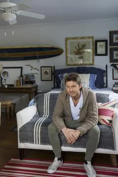 Man sitting on sofa at end of bed Stock Photos