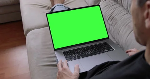 Man sitting on sofa in front of laptop with green screen, chroma key, makes vide Stock Footage 138266450