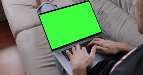 Man sitting on sofa in front of laptop with green screen, chroma key, makes vide Stock Footage 138267014