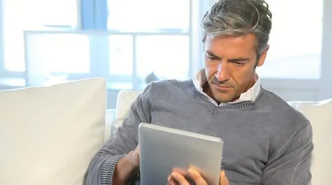 Man sitting in sofa at home with electronic tablet Stock-Footage 14830309