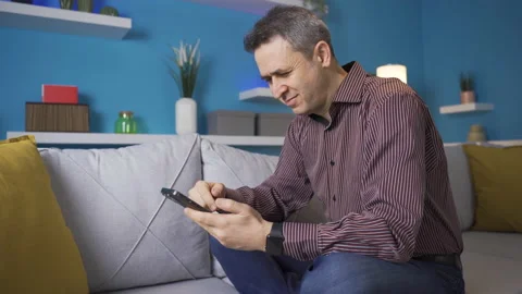 Man sitting on sofa at home looking at phone. Stock Footage 233305393