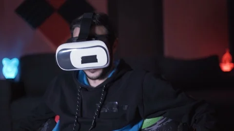Man sitting on sofa at home playing games and watching movies with VR glasses Stock Footage 120454658