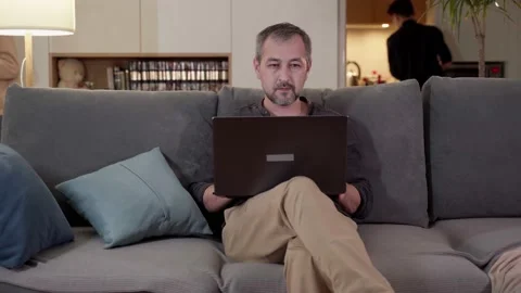 A man is sitting on a sofa with a laptop. Remote work, online. Video stock 179528076
