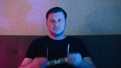 A man sitting on a sofa slowly puts on stereo glasses. Video stock 131341537