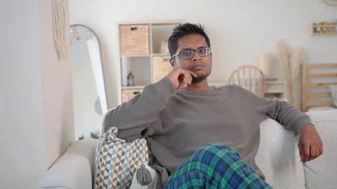 Man sitting on sofa thinking and relaxing Stock Footage 345014644