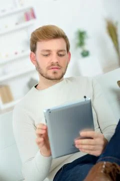 Man sitting in sofa using electronic tablet Stock Photos