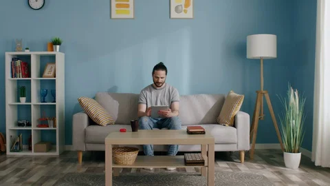 Man Is Sitting on Sofa Using Gadget to Stay in Touch Video stock 129894460