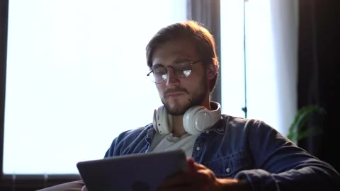 Man sitting on sofa, using gadget, tablet computer, staying busy on weekend. Stock Footage 143911728