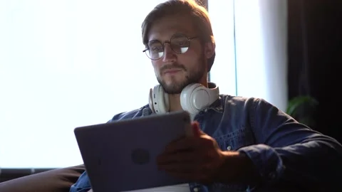 Man sitting on sofa, using gadget, tablet computer, staying busy on weekend. Stock Footage 143911771