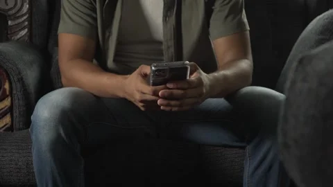Man sitting on sofa using smartphone Stock Footage 317056095