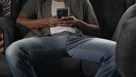 Man sitting on sofa using smartphone Stock Footage 317056115