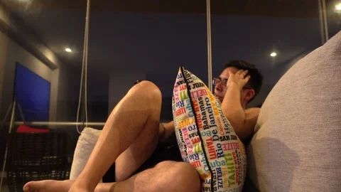 A man sitting on the sofa watching tv resting after work with cushions and Video stock 172271337