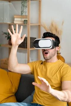 Man sitting on sofa wearing virtual reality goggles. Stock Photos