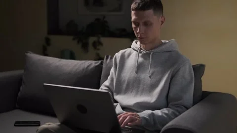 Man sitting on sofa working on laptop in indoor space. Calm evening atmosphere Stock Footage 314555278