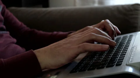 The man sitting on the sofa works with the laptop typing on the keyboard. Stock Footage 239014643