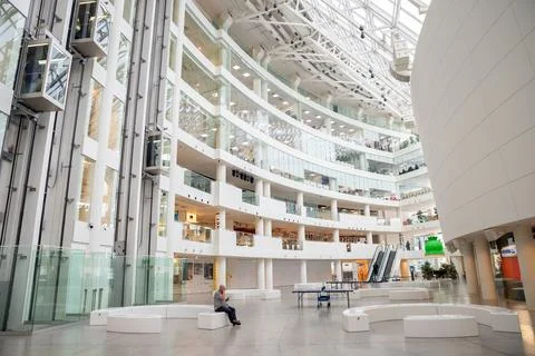 Man sitting in the spacious white interior of a modern cultural center Stock Photos