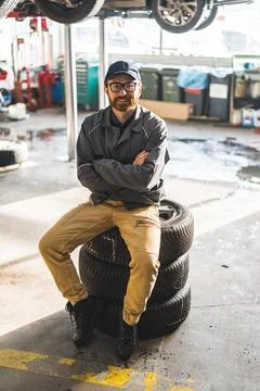Man sitting on a stack of car wheels in modern and well equipped car repair shop Stock Photos