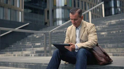 Man sitting at stairs and using tablet pc Stock Footage 92090097