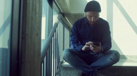 Man sitting on stairs using smartphone Stock Footage 62948078