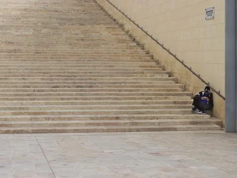 Man sitting on stairs while playing with his phone. Stock-Fotos