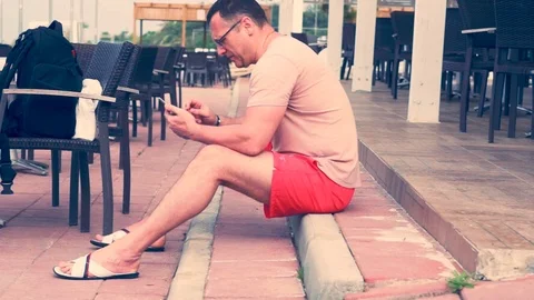 Man sitting on steps at a restaurant Stock-Footage 94061463