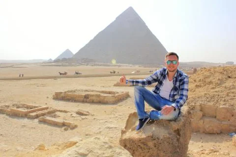 Man sitting on the stone with pyramids background Foto stock