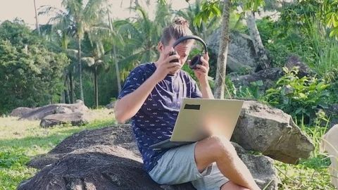 A man is sitting on the stone while working as a freelancer. Video stock 122498658
