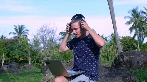 A man is sitting on the stone while working as a freelancer. Video stock 122498881