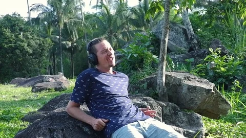 A man is sitting on the stone while working as a freelancer. Video stock 122498957