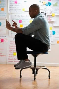 Man sitting on stool with digital tablet Foto stock