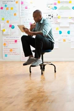 Man sitting on stool with digital tablet Foto stock