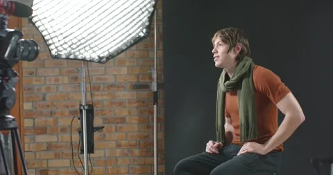 Man sitting on stool during interview, turning toward crew gesture by camera, Stock Footage 347753348