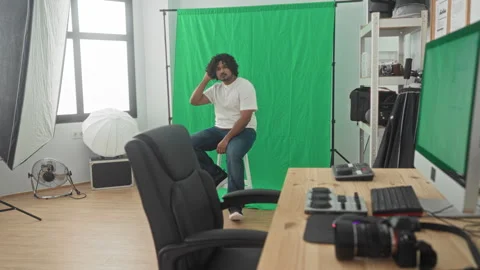 Man sitting on stool with hands clasped and neutral gaze, wearing white tsh.. Stock Footage 337396058