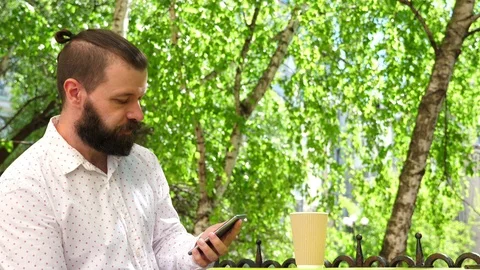 A man is sitting in a summer cafe with a cup of coffee. Stock Footage 89155909