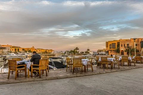 Man sitting in the sunset at a table close to the marina Stock Photos