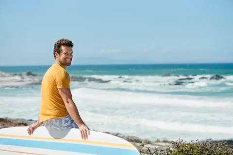 Man sitting on a surfboard on the beach Stock Photos