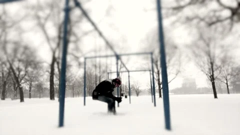 Man Sitting in a Swing at a Park during Snow Storm Stock Footage 162257025