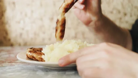 A man is sitting at a table and eating mashed potatoes with sausages Stock Footage 199533770