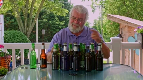 A man is sitting at a table in a backyard, looking at a collection of different Stock Footage 318904662