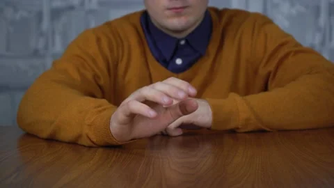 A man sitting at the table bangs his fingers on the table due to stress Stock Footage 145344717
