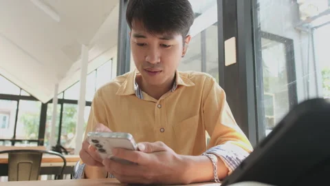 Man is sitting at a table with a cell phone in his hand Stock Footage 303532752