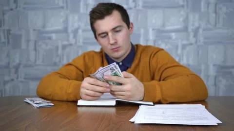 A man sitting at the table counting his money 스톡 동영상 145219853